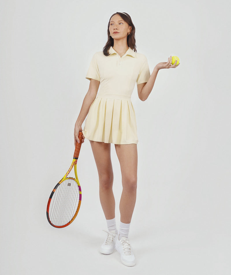 Woman in a yellow tennis outfit holding a racket and a tennis ball on a white background
