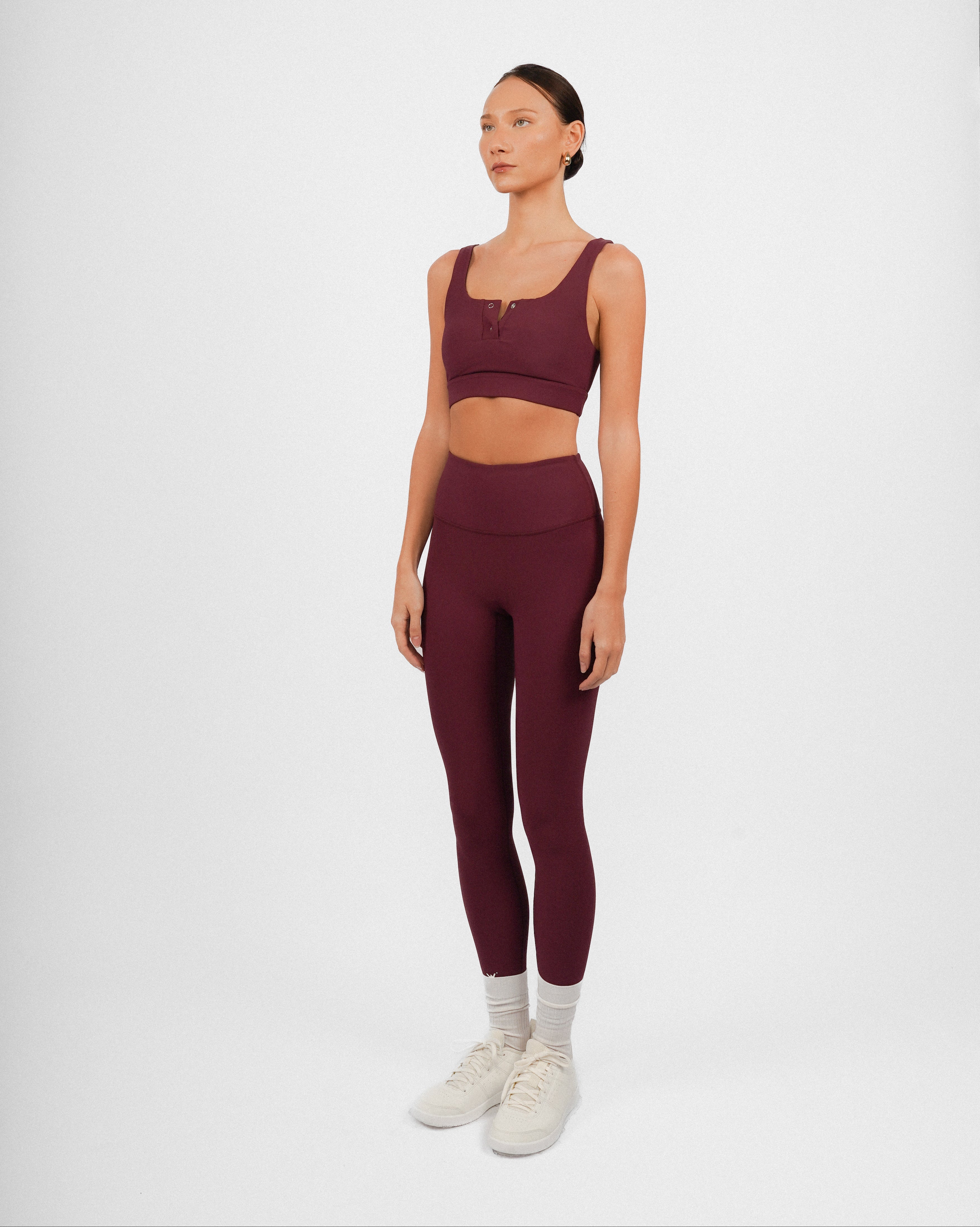 Woman wearing a burgundy athletic outfit on a white background