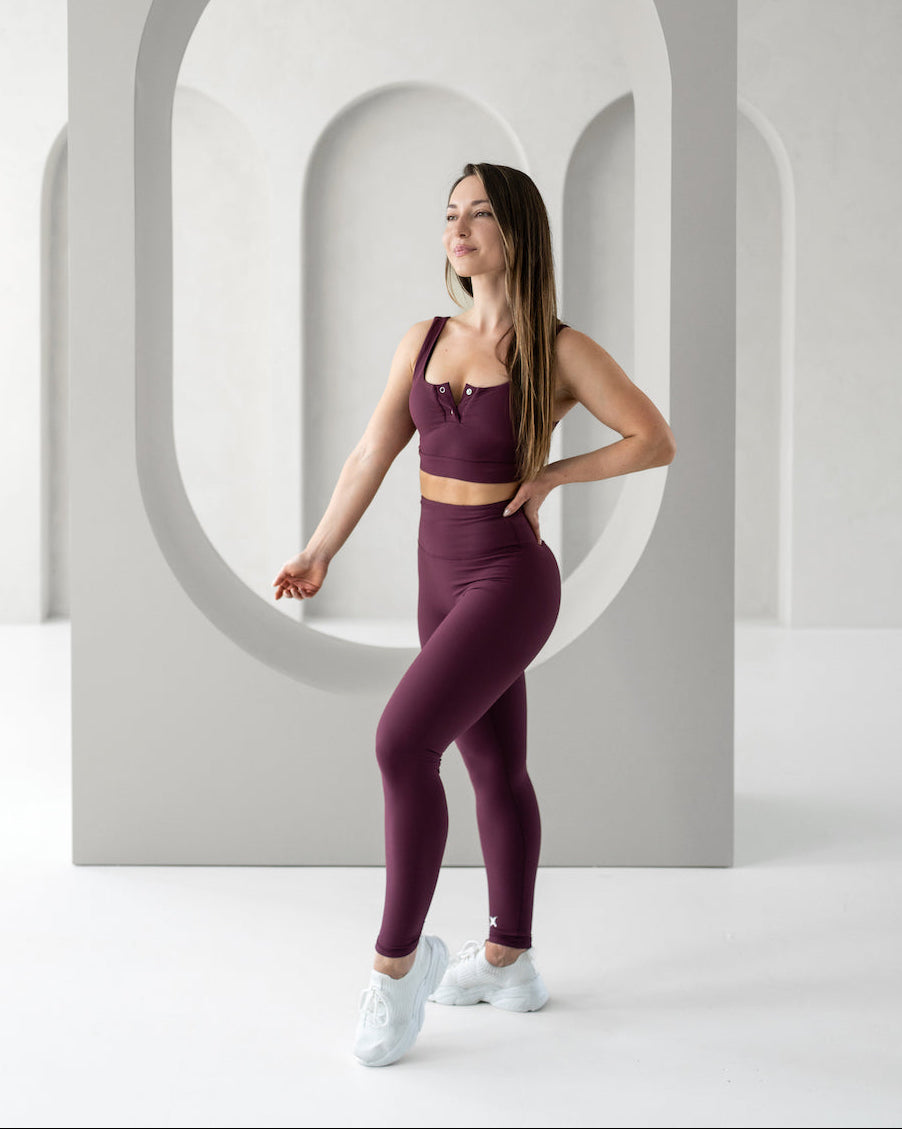 Woman in purple athletic wear standing in a modern, minimalistic setting